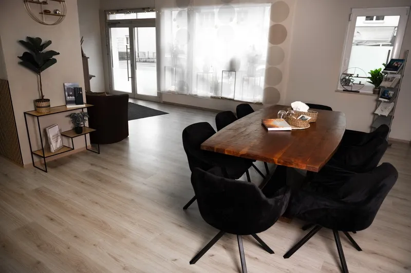Einladender Beratungsraum mit Holztisch und schwarzen Polsterstühlen im Bestattungshaus Schmitz in Weiden.